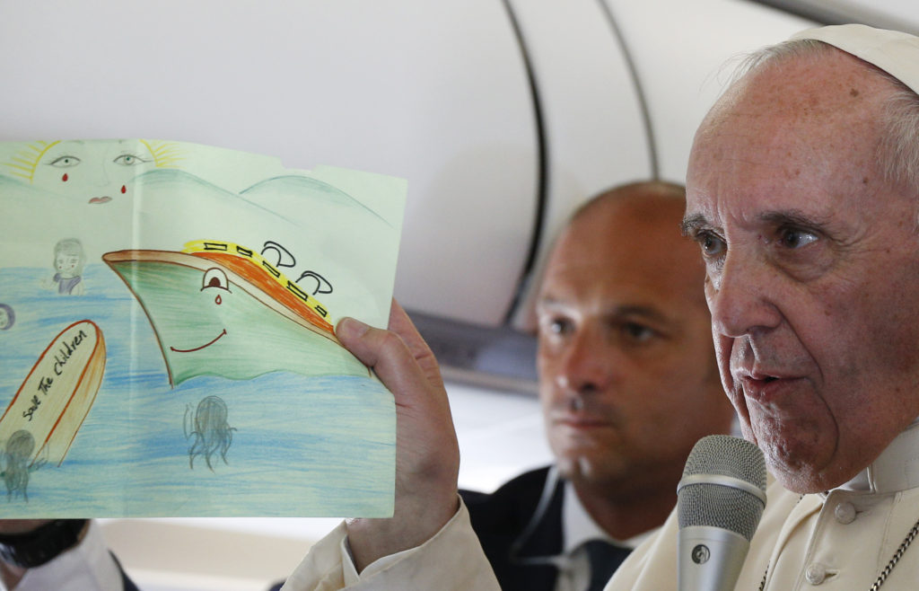 Pope Francis shows a drawing given by a child in a refugee camp as he answers questions from journalists aboard his flight from the Greek island of Lesbos to Rome April 16. The drawing, which shows the sun crying, was given by a child at the Moria refugee camp in Lesbos where the pope met 250 people. (CNS photo/Paul Haring) 