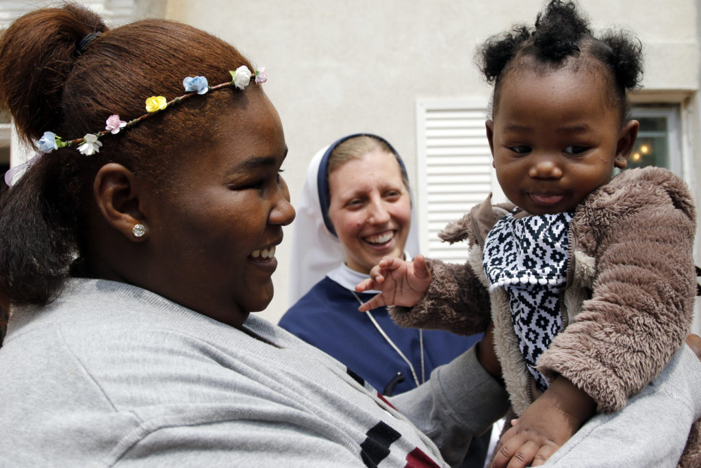 A woman holds her baby as Sr. Brigid Ancilla, a member of the Sisters of Life, looks on during the annual Mother's Day celebration May 8 at the religious community's retreat house in Stamford, Conn. Founded 25 years ago, the Sisters of Life provide outreach to pregnant women in crisis and offer continuing support to them following the birth of their children. More than 70 women and 200 children ministered to by the nuns attended this year's celebration. (CNS photo/Gregory A. Shemitz) 