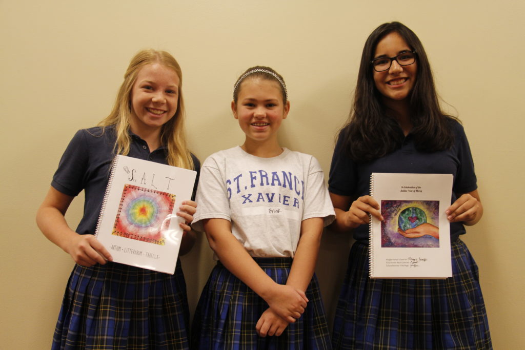 Maggie Kamps, Kate Brink and Juliana Ramirez, students at St. Francis Xavier, show off the school's literary publication focused on mercy. (Ambria Hammel/CATHOLIC SUN)