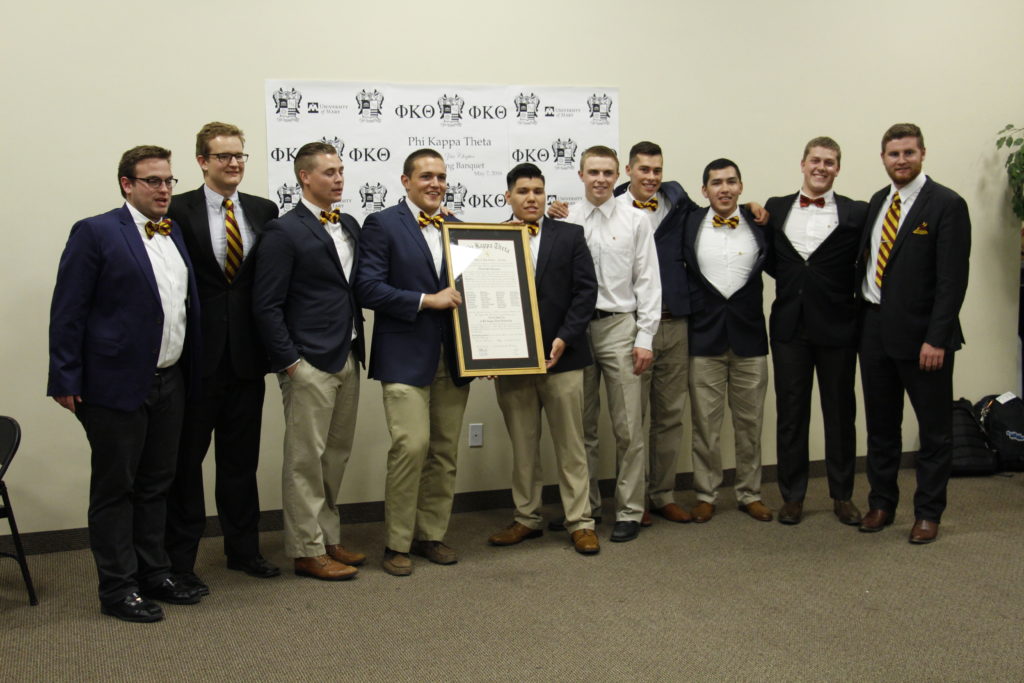 Several founding members of the Alpha Zeta chapter of the Phi Kappa Theta fraternity pose with the chartering document May 7 at the All Saints Catholic Newman Center. (Ambria Hammel/CATHOLIC SUN)