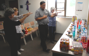 Dcn. ___ blesses food packages for the homeless as St. Joseph parishioners Gretchen Larson, Becky Sanchez and Glenda Coen join him in prayer. (Ambria Hammel/CATHOLIC SUN)