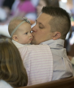 Joseph Niedzielski kisses his 5-month-old daughter, Colette, during Mass at Jesus the Divine Word Church in Huntingtown, Md. in this 2014 file photo. Fathers are honored in special ways on Father's Day, which is celebrated June 19 this year. (CNS photo/Bob Roller) 
