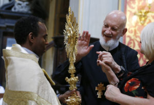 Redemptorist Father Cyril Axelrod, who is deaf and blind, touches a monstrance during exposition of the Eucharist at Chiesa Nuova in Rome June 10. The South African priest, who travels the world ministering to deaf Catholics, said that sign language, tactile sign language and body language are "gifts of the Holy Spirit." He was in Rome for the Year of Mercy jubilee celebration for the sick and persons with disabilities. (CNS photo/Paul Haring) 