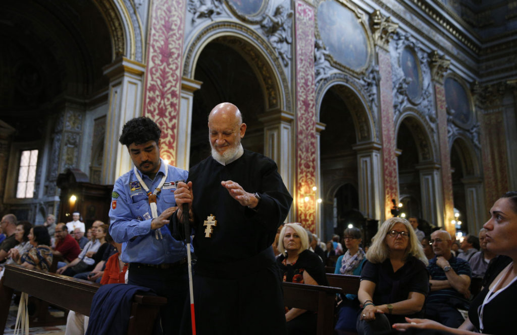 Redemptorist Father Cyril Axelrod, who is deaf and blind, is helped by scout Orazio Pemmisi, who is deaf, as he prepares to speak at Chiesa Nuova in Rome June 10. The South African priest, who travels the world ministering to deaf Catholics, said that sign language, tactile sign language and body language are "gifts of the Holy Spirit." He was in Rome for the Year of Mercy jubilee celebration for the sick and persons with disabilities. (CNS photo/Paul Haring) 