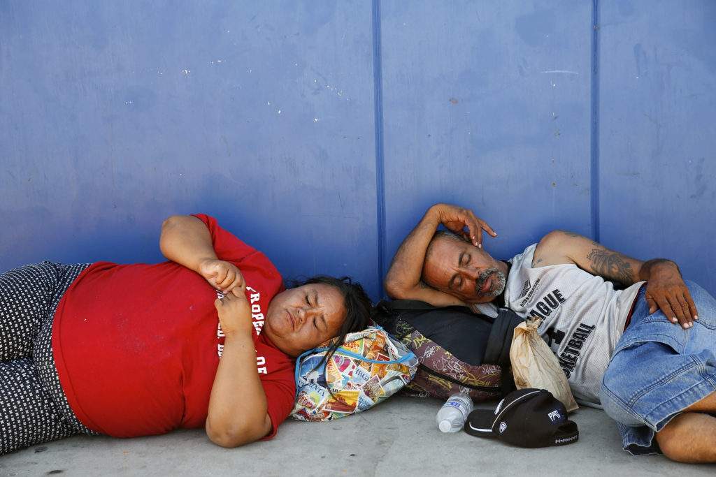 Corina Cristan, left, naps alongside an unidentified man in a strip of shade outside the main dining hall of the Society of St. Vincent de Paul in Phoenix June 14. Phoenix temperatures are expected to reach all-time highs this summer putting the homeless and others at greater risk for heat-related illness. (CNS photo/Nancy Wiechec) 