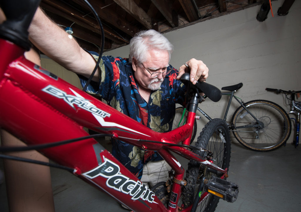 Tom Mayhew tests the brakes on a bicycle in the basement of St. John the Evangelist Church rectory in Green Bay, Wis. Mayhew, a retired dentist, was homeless and turned to the shelter after his practice went bankrupt. Now back on his feet, he says repairing bikes is a way for him to give back to the shelter. (CNS photo/Sam Lucero, The Compass) 