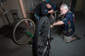 Tom Mayhew, right, and Mike Mooney repair the brakes on a bicycle June 7 in the basement rectory of St. John the Evangelist Church in Green Bay, Wis. The room serves as a repair center for Spokes 4 Hope, a bicycle repair program in cooperation with St. John the Evangelist Homeless Shelter. (CNS photo/Sam Lucero, The Compass) 
