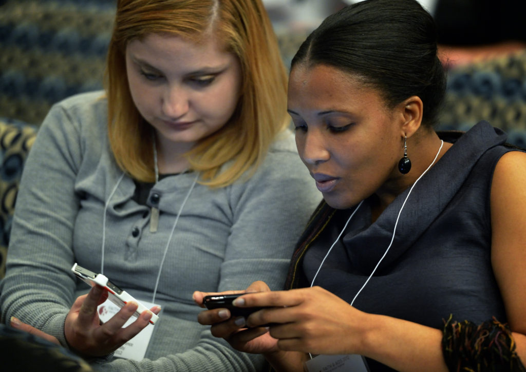 Young women tweet messages during a 2012 conference in Washington. Low-cost video messaging carried across increasingly video-friendly social media platforms will define this year's World Youth Day experience in Krakow, Poland, say several organizations. (CNS photo/Paul Jeffrey) 