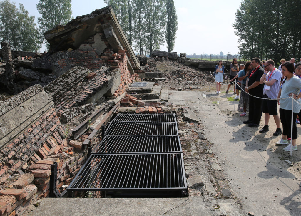 Father Robert Adamo, pastor of St. Ephren Church in Brooklyn, N.Y., prays near the site of gas chambers during a July 25 visit to the Birkenau Nazi concentration camp in Oswiecim, Poland. Father Adamo and other pilgrims from the diocese were in Poland for World Youth Day. (CNS photo/Bob Roller) 