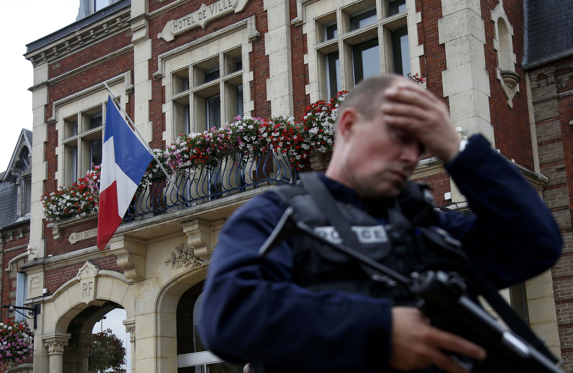 A policeman reacts as he secures a position in front of city hall after two assailants killed 84-year-old Father Jacques Hamel and took five people hostage during a weekday morning Mass  at the church in Saint-Etienne-du-Rouvray, France, near Rouen July 26. (CNS photo/Pascal Rossignol/Reuters) 