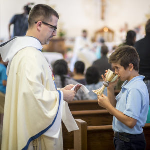 For the first time as a Franciscan Friar of the Holy Spirity, Fr. Benedict Mary Lieb, FHS, presents the Precious Blood to a young man during the July 2 Mass. (Billy Hardiman/CATHOLIC SUN)