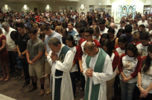 Family and friends of the diocese's more than 200 pilgrims headed to World Youth Day in Poland extend their hands over the teens, young adults and chaperones during a July 12 sendoff Mass at St. Andrew the Apostle in Chandler. (Ambria Hammel/CATHOLIC SUN)