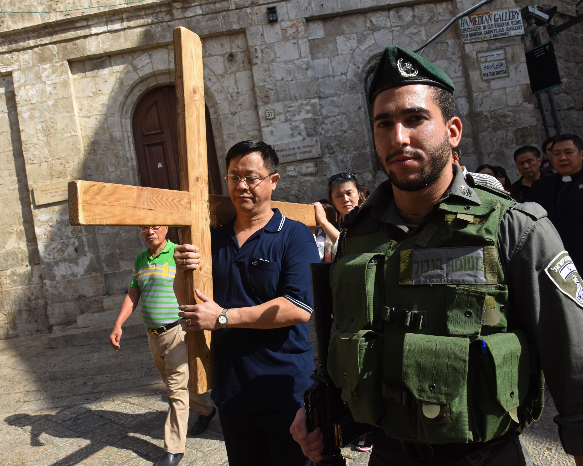 An Israeli border police officer stands near Catholic tourists from Indonesia as they carry a cross Oct. 18 on the Via Dolorosa in Jerusalem's Old City, near a site where several recent stabbings have taken place. (Debbie Hill/CNS)
