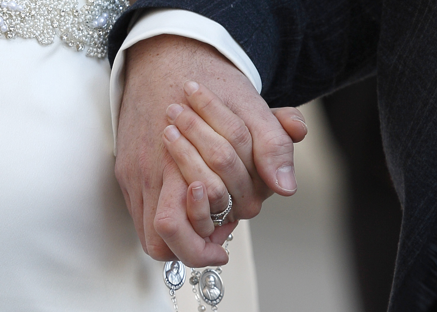 A newly married couple hold rosaries in their hands as they leave Pope Francis' general audience in St. Peter's Square at the Vatican Feb. 24. Three U.S. bishops wrote issued a joint statement reaffirming the definition of marriage as between one man and one woman and the obligation of Catholic polititicans to uphold their faith in public, following a tweet sent by Vice President Joe Biden officiating a same-sex wedding ceremony. (CNS photo/Paul Haring)