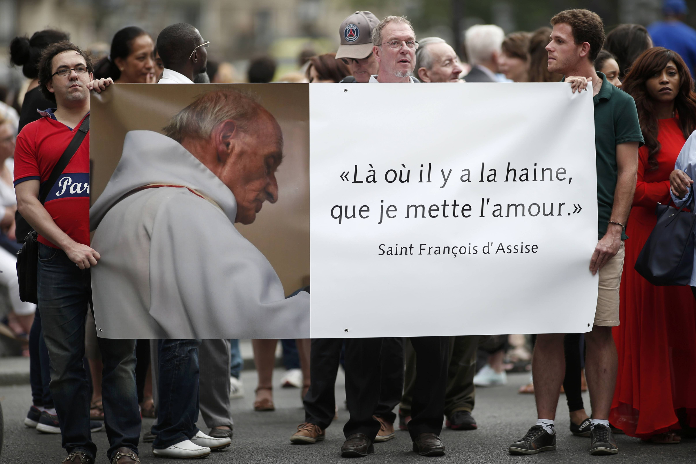 People hold a banner with a picture of French priest Father Jacques Hamel, which reads, "Where there is hatred, let me sow love," after a July 27 Mass at the Notre Dame Cathedral in Paris. Father Jacques Hamel was killed in a July 26 attack on a church at Saint-Etienne-du-Rouvray near Rouen by assailants linked to Islamic State groups. (CNS photo/Benoit Tessier, Reuters)
