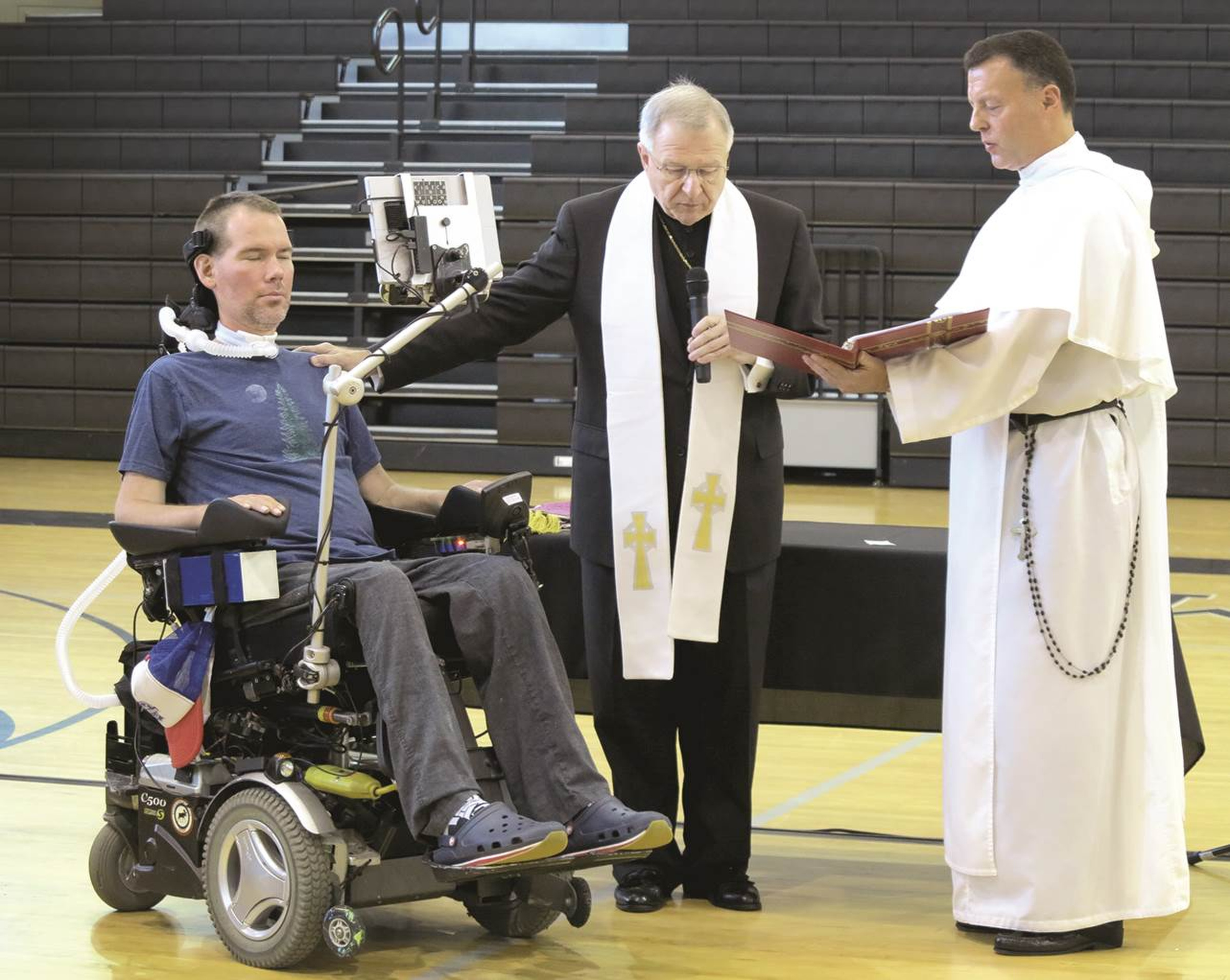 New Orleans Archbishop Gregory M. Aymond confers the sacrament of the sick June 18 on former New Orleans Saints special teamer Steve Gleason, who has been battling amyotrophic lateral sclerosis, or ALS, since 2011 and has established a foundation to help others with the disease get the assistive "eye-tracking" technology to help them communicate. (CNS photo/Christine Bordelon, Clarion Herald) See SAINTS-GLEASON-FAITH Aug. 2, 2016.