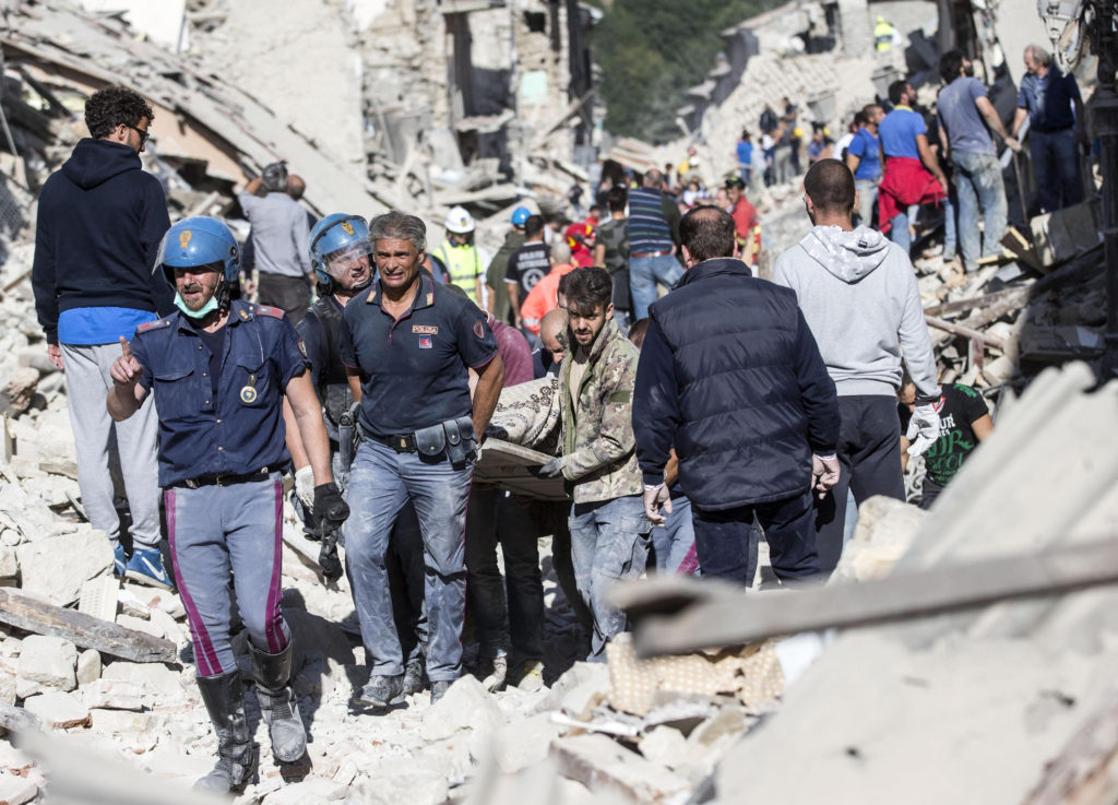 Rescuers carry an injured man in Amatrice, Italy, following an earthquake Aug. 24. (CNS photo/Massimo Percossi, EPA)