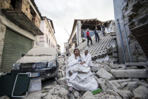 Residents sit on the rubble of collapsed buildings in Amatrice, Italy, following an earthquake Aug. 24. (CNS photo/Massimo Percossi, EPA)