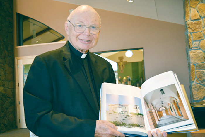 Fr. Peter Dobrowski, former pastor of St. Margaret Mary Parish in Bullhead City, holds a copy of “Traditional Architecture” by Alireza Sagharchi and Lucien Steil, which featured the Bullhead City church. (Lisa Dahm/CATHOLIC SUN)
