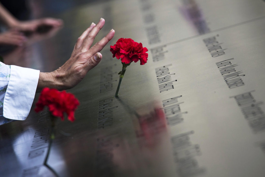 A woman touches a carnation left on a name inscribed into the North Pool during 9/11 memorial ceremonies in 2013. The attacks claimed the lives of nearly 3,000 people in New York City, Shanksville, Pa., and at the Pentagon. (CNS photo/Adrees Latif, Reuters) (Sept. 11, 2013)