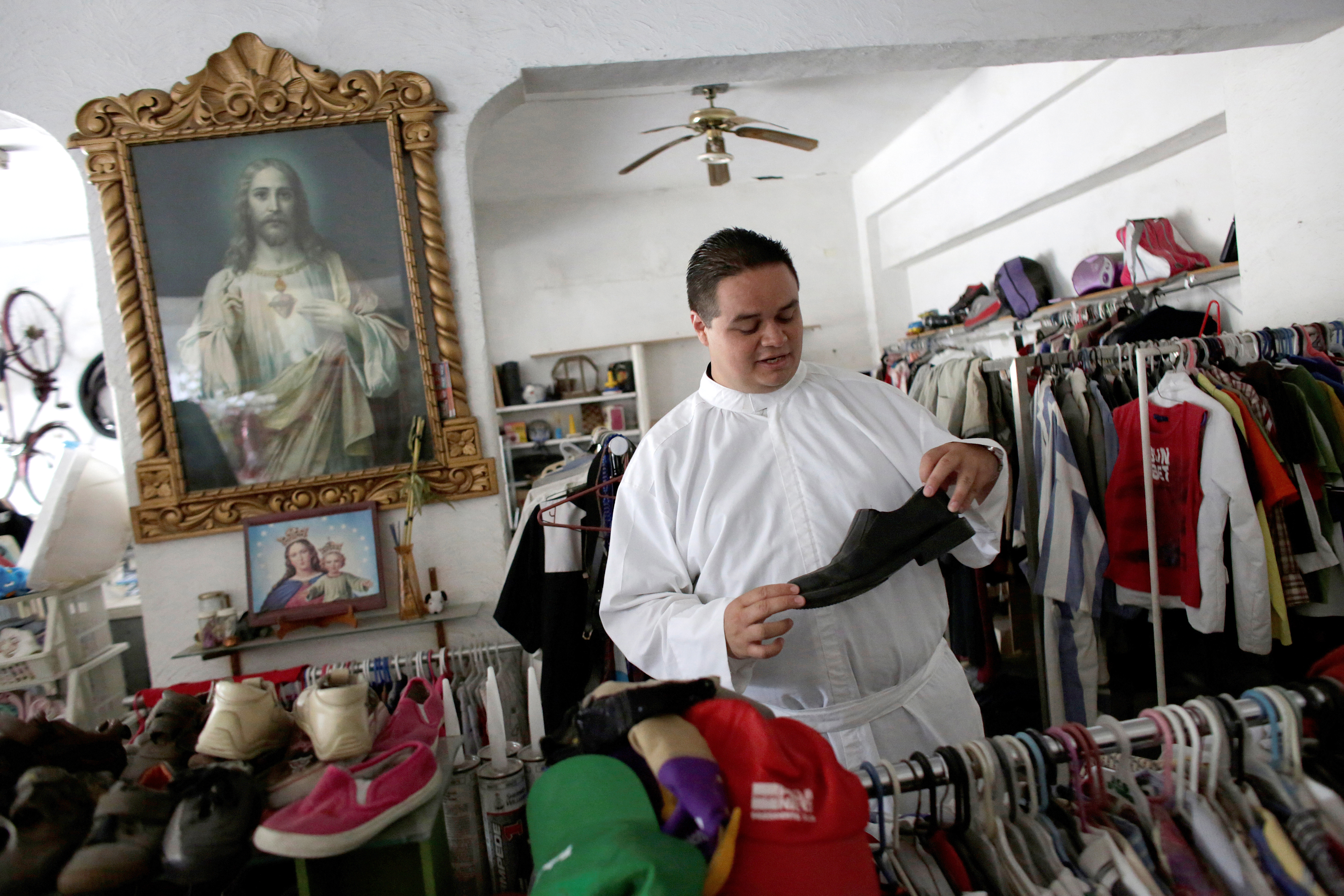Fr. Jose Luis Guerra checks shoes at a second-hand shop July 27 on the outskirts of Monterrey, Mexico. Fr. Guerra works with gang members with his own group, dubbed the Gang of Christ. (CNS photo/Daniel Becerril, Reuters)