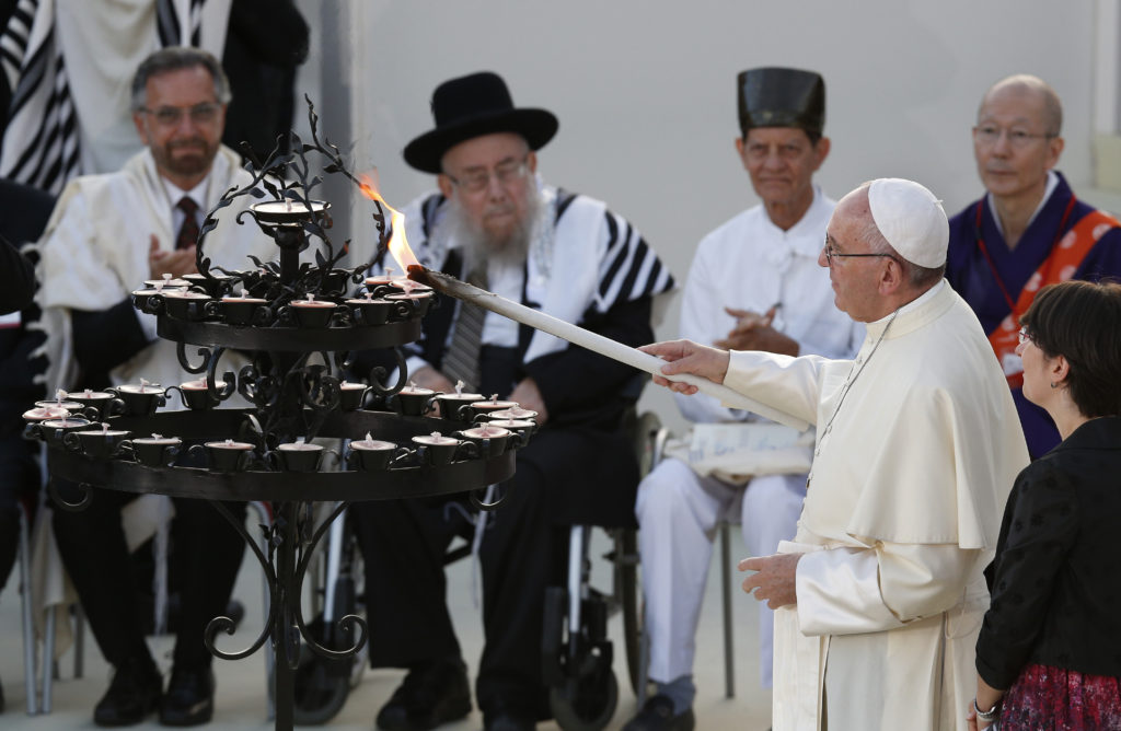 Pope Francis lights a candle during an interfaith peace gathering outside the Basilica of St. Francis in Assisi, Italy, Sept. 20. The pope and other religious leaders were attending a peace gathering marking the 30th anniversary of the first peace encounter. (CNS photo/Paul Haring) 