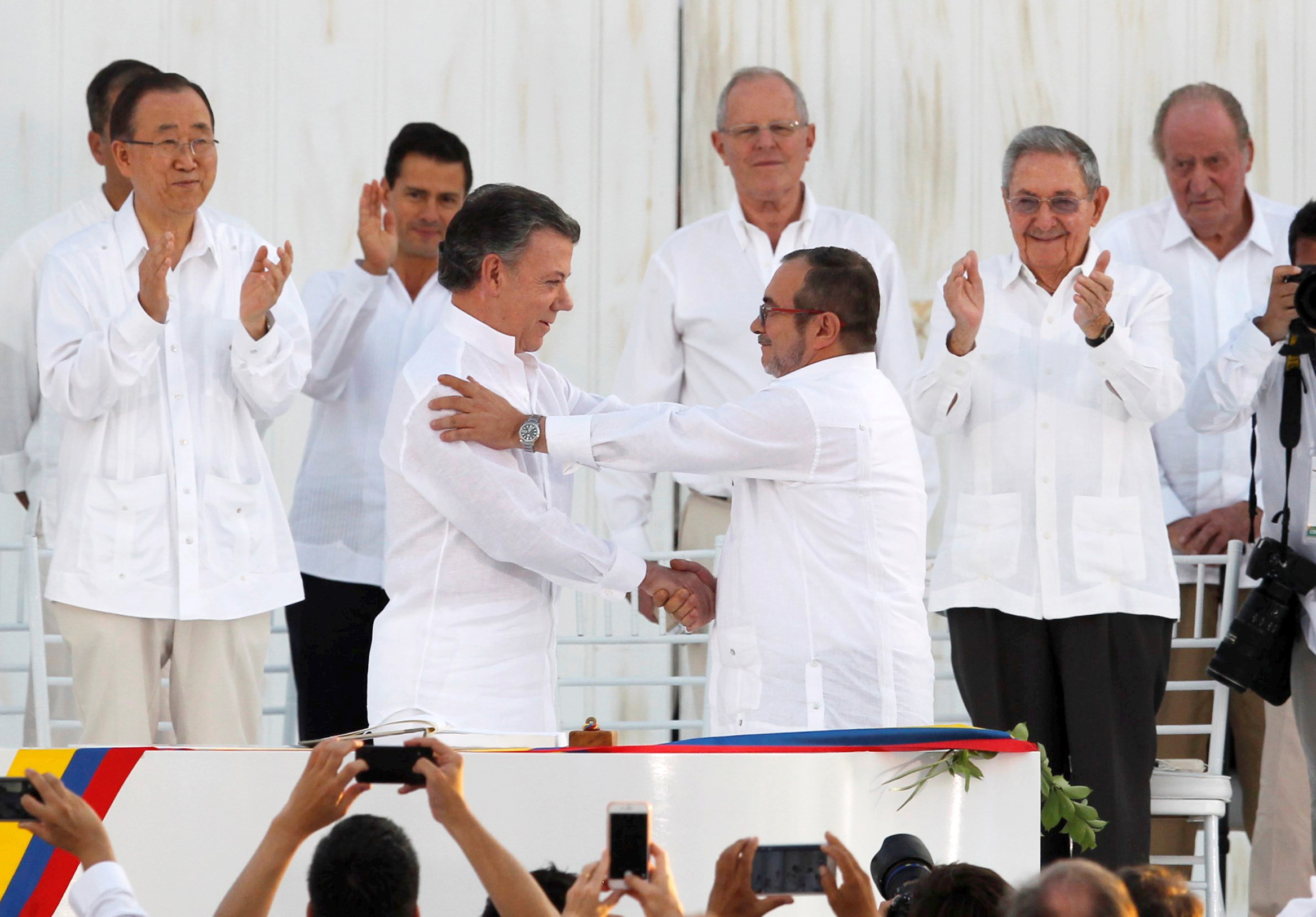 Colombian President Juan Manuel Santos and Marxist rebel leader Rodrigo Londono Echeverri of FARC, the Revolutionary Armed Forces of Colombia, shake hands Sept. 26 in Bogota after signing an agreement to end Latin America's last armed conflict. (CNS photo/John Vizcaino, Reuters)