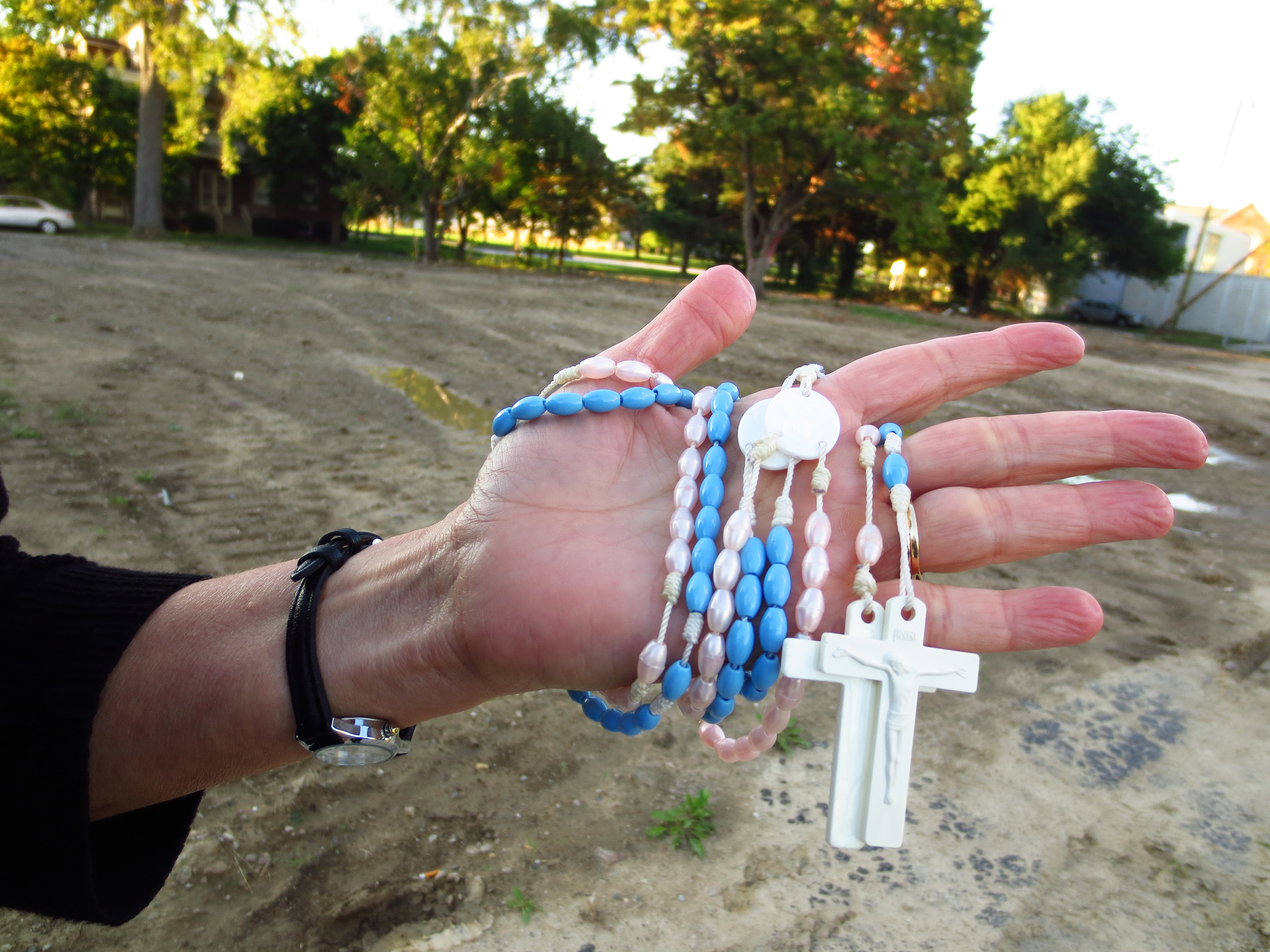 Pro-life activist Ann Barrick holds rosaries Sept. 26 while standing on the former site of the Center for Choice abortion clinic in Toledo, Ohio. These are the pink and blue rosaries she used while praying outside the clinic, which was closed in 2013 and torn down this September. The property is slated to be converted into a memorial for the unborn called "Hope Park." (CNS photo/Katie Breidenbach)