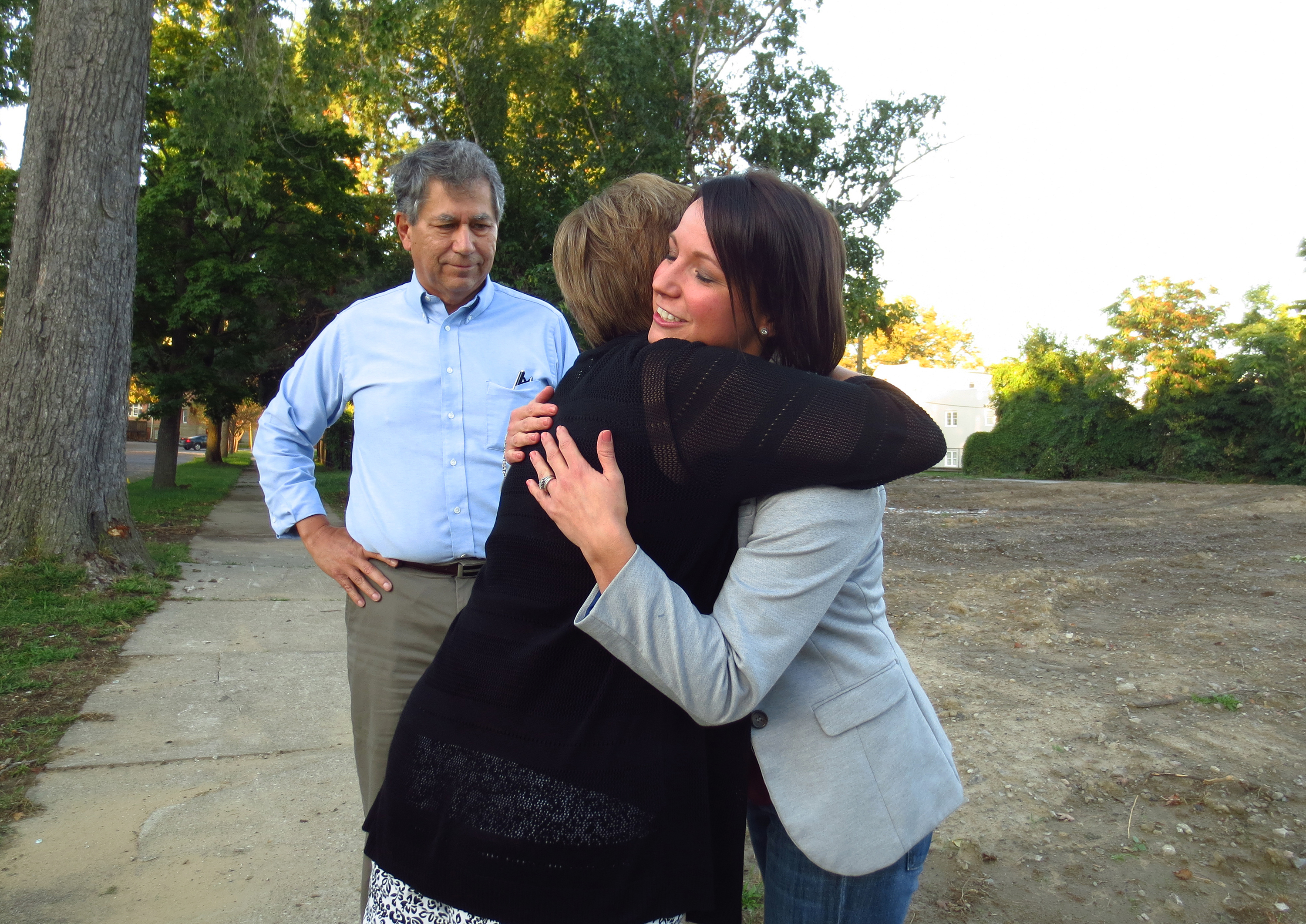 Mandy Sattler, right, gets a hug from pro-life activist Ann Barrick Sept. 26 at the site of the now-demolished Center for Choice abortion clinic in Toledo, Ohio. Looking on is Ed Sitter, executive director of the Foundation for Life. Barrick prayed outside the abortion clinic for nine years and Sattler had an abortion there 10 years ago. (CNS photo/Katie Breidenbach) 