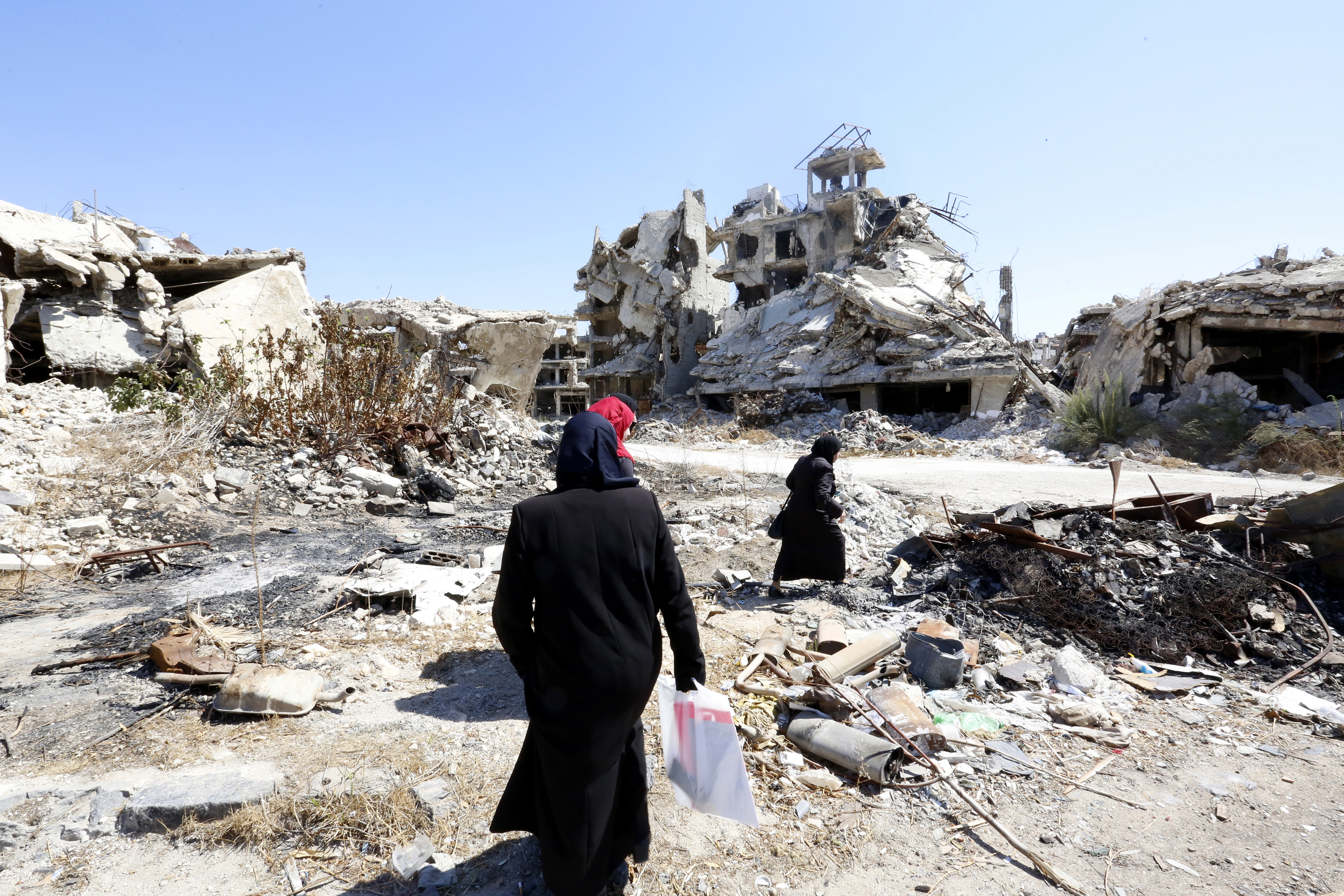 People walk amid rubble Sept. 19 in the city of Homs, Syria. (CNS photo/Mohammed Badra, EPA)
