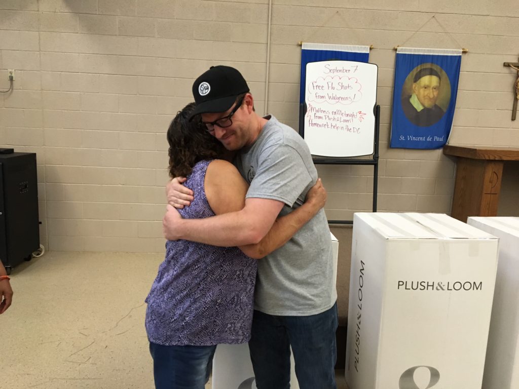 Plush & Loom President Caleb Porter hugs a mother from St. Vincent de Paul's dining room, who received the first free mattress during the launch celebration event. (photo courtesy of St. Vincent de Paul)
