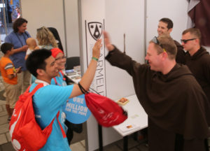 Carmelit Brother Kevin Kelly of the Chicago province gives a high five to pilgrims from Indonesia at the World Youth Day evangelization center July 29 in Krakow, Poland. (CNS photo/Bob Roller) 