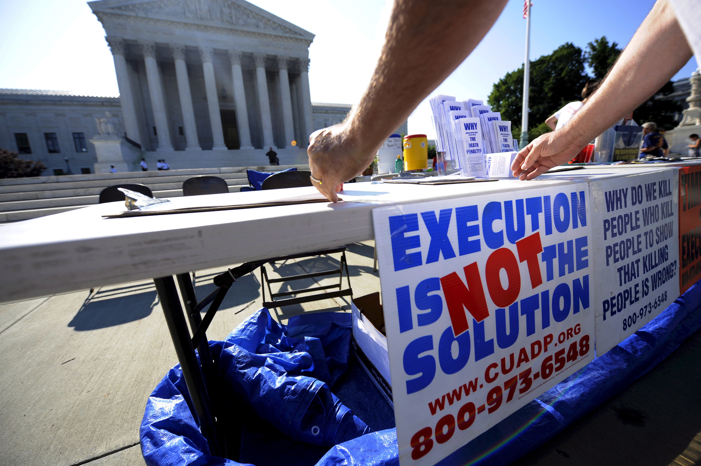 A member of the Abolition Action Committee hangs a sign in front of the Supreme Court in Washington during a 2008 vigil to abolish the death penalty. (CNS photo/Shawn Thew, EPA)