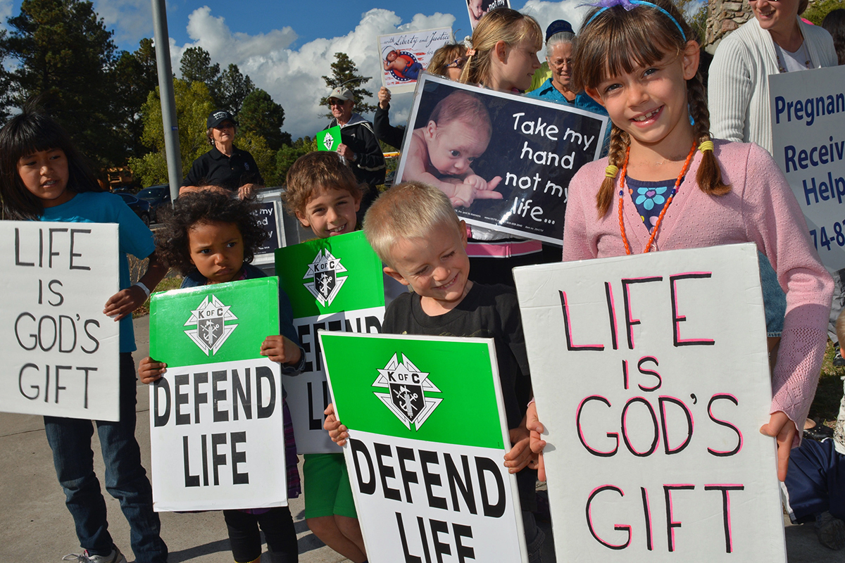 From left to right, Vaneshia MacArthur, Elizabeth DeWitt, Benjamin Cook, Ezra Copeland and Zoe Copeland hold signs on the corner in front of the shopping center with Planned Parenthood in Flagstaff on Oct. 2. The students were supporting the 40 Days of Life international vigil. (Lisa Dahm/CATHOLIC SUN)