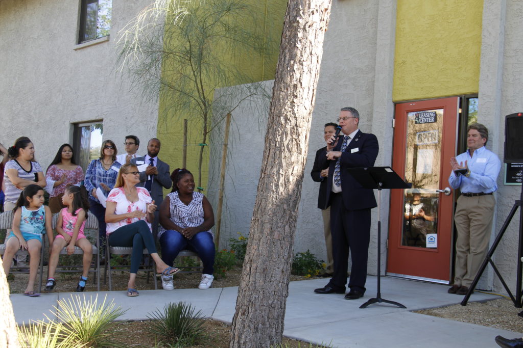 Residents of Desert Willow (seated) listen to Paul Mulligan, president and CEO of Catholic Charities, during their apartment's grand re-opening celebration Sept. 27. (Ambria Hammel/CATHOLIC SUN)