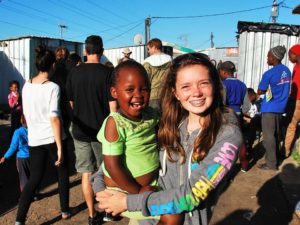 Annie Caris (XCP ‘18) carries local child on tour of Lanka township, South Africa (courtesy photo)