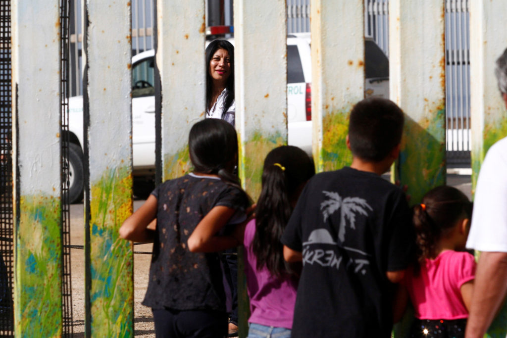 A woman in San Diego talks through a fence with children in Tijuana, Mexico, Nov. 12. (CNS photo/Jorge Duenes, Reuters) 