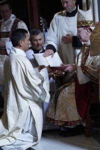 Dcn. Billy Chavira receives the Book of the Gospels from Bishop Olmsted, being told to “Believe what you read, teach what you believe, practice what you teach.” (Ambria Hammel/CATHOLIC SUN)