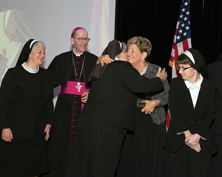 Sr. Martha Mary Carpenter, principal of St. Peter Indian Mission School, hugs Catholic Schools Superintendent MaryBeth Mueller after her order, the Franciscan Sisters of Charity, received the Guardian of Hope award for their work at the school. Looking on is Bishop Thomas J. Olmsted and the other members of the Franciscan Sisters of Charity. (Photo courtesy of Catholic Schools Office)