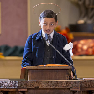 A young man dressed as St. Dominic Savio serves as a lector for the Vocations Celebration Mass Oct. 30. (Billy Hardiman)
