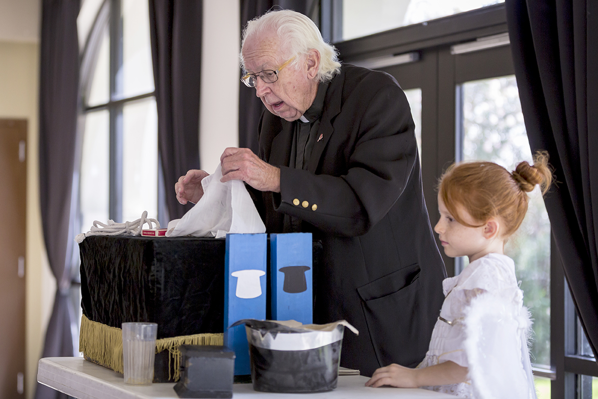 With the assistance from a guardian angel, Holy Cross Father Jim Blantz performs a magic show. (Billy Hardiman/CATHOLIC SUN)