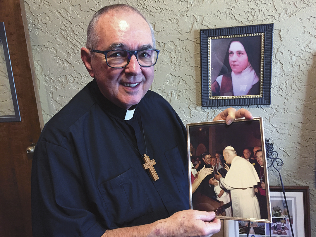 Fr. Doug Lorig, shown here with a portrait of St. Thérèse of Lisieux and a cherished photo of his encounter many years ago with St. John Paul II, will soon step down as pastor at St. Maria Goretti Parish in Scottsdale. (Joyce Coronel/CATHOLIC SUN)