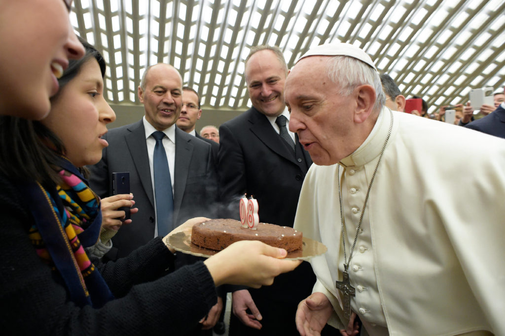 Pope Francis blows out candles on a birthday cake presented by a woman during his general audience in Paul V hall at the Vatican Dec. 14. The pope will turn 80 Dec. 17. (CNS photo/L'Osservatore Romano, handout) 