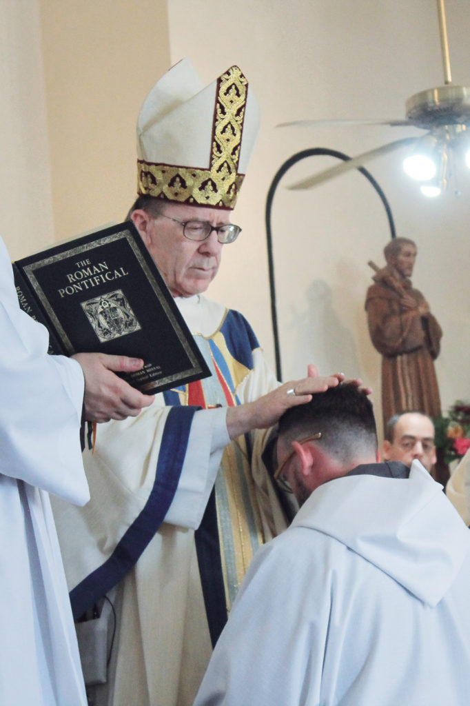 Bishop Olmsted lays hands on Br. Athanasius, ordaining him to the transitional diaconate. The ordination was the first for the newly established Franciscan Friars of the Holy Spirit and the first in the history of the 47-year diocese to take place on a Native American reservation. (Tony Gutiérrez/CATHOLIC SUN)